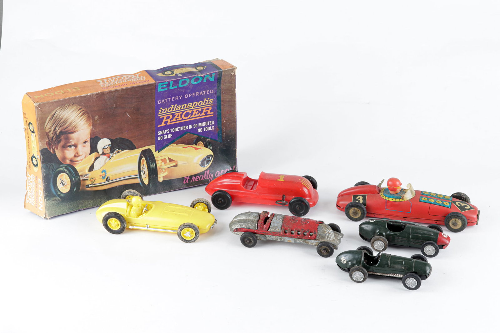 6 TOY RACE CARS: Six toy race cars, two 'Scalextric' slot cars, 6 inches long. 'Eldon Battery Operated Indianapolis Racer' in the original box, used box with damage. 8 inches long, Wind-up race car with driver, 10 inc