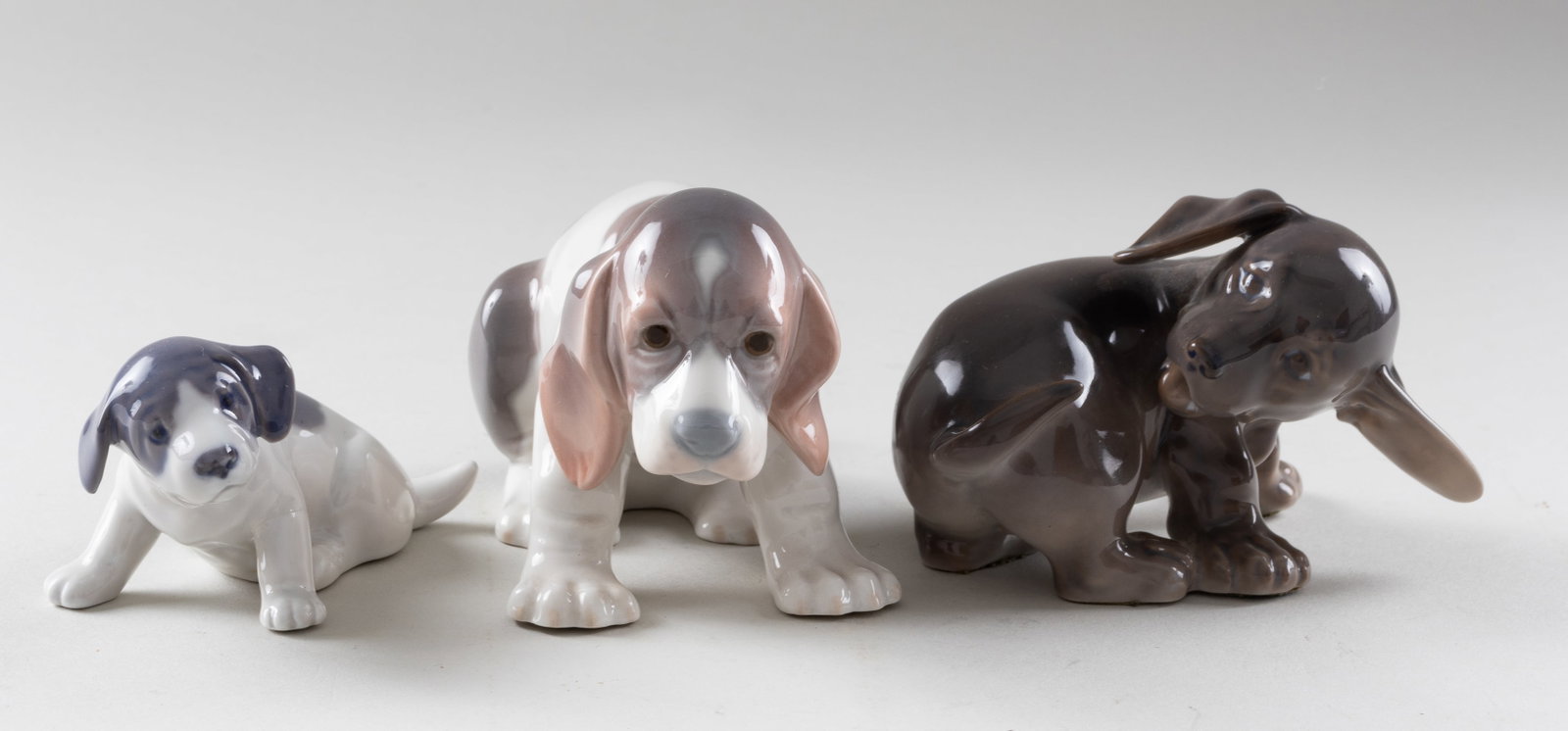 3 LLADRO AND ROYAL COPENHAGEN PORCELAIN DOGS: Three Lladro and Royal Copenhagen porcelain dogs, approx 3 inches tall each dog. All dogs in a sitting position.