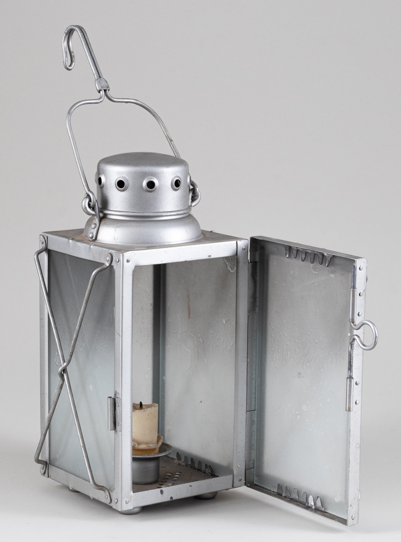 LUFTWAFFE FIELD LANTERN: Aluminum chassis with clouded glass coverings, room inside for candle. On the bottom is stamped 'FL. U.V.' for Flieger-Unterkunftsverwaltung, and below is the maker stamp M.W.N 4. 10.75 x 5.5 x 5.5 in