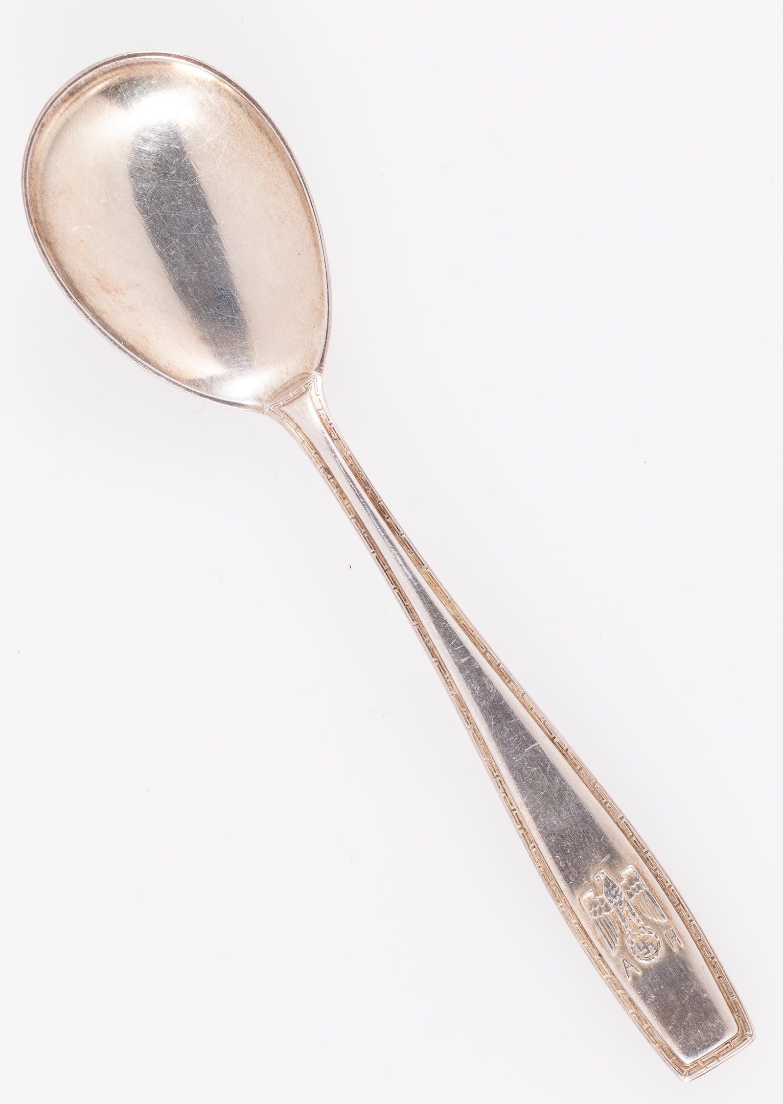 ADOLF HITLER FORMAL DESSERT SPOON: Adolf Hitler formal style dessert spoon. Featuring a Roman key design border around the handle, embossed with the Reichseagle flanked by an A and H. Reverse is stamped '800' silver with crescent and c
