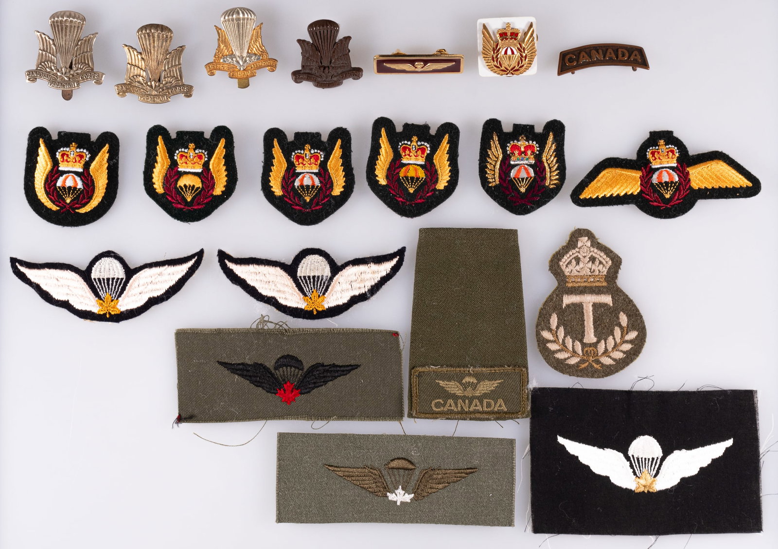 CANADIAN PARATROOPS WINGS BADGES AND INSIGNIA: 20 Canadian Paratroopers Wings badges and sleeve insignia, featuring: 1) three Canadian Parachute Corps cap badges, one black plastic variety. 2) Canadian Airborne Regiment cap badge, in French. 3) fi