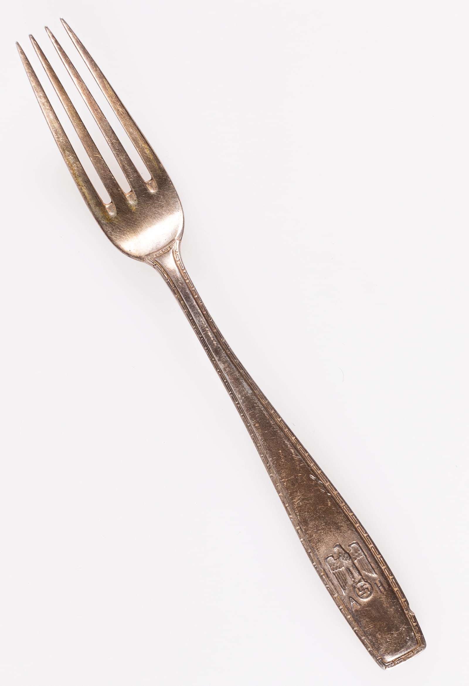 ADOLF HITLER FORMAL PATTERN FORK: Adolf Hitler's formal pattern demitasse spoon. Depicts a German political eagle clutching a swastika in its talons, letters 'AH' marked below. Has a formal Grecian key pattern around the edge. On the 
