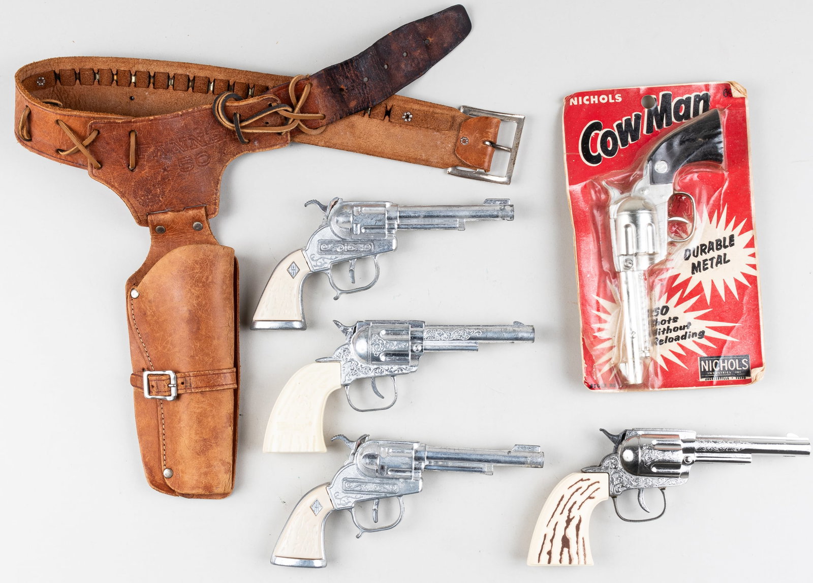 NICHOLS, DAISY; 5 TOY CAP GUNS AND HOLSTER: Lot of five toy cap guns including Nichols 'CowMan' revolver in original packaging, partially opened at the bottom of the package, 9.5 x 5.75 inches; Daisy cap pistol revolver, 7.75 inches long; two C