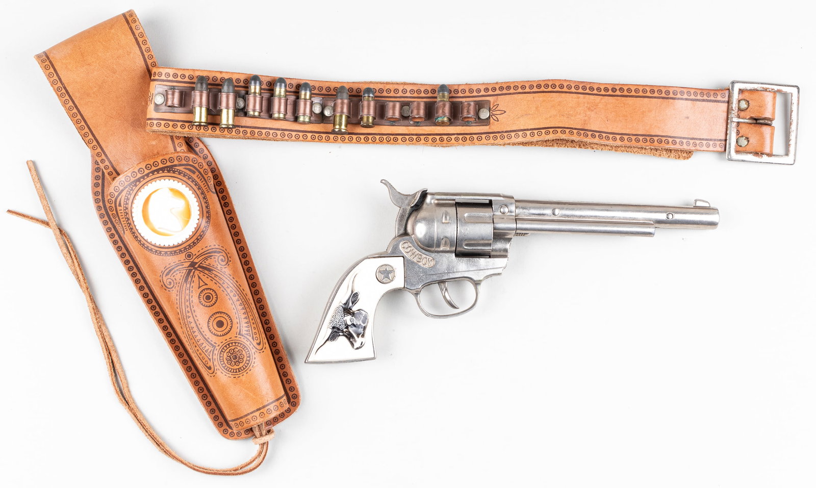 HUBLEY REVOLVER CAP GUN WITH HOLSTER: Hubley 'Cowboy' die-cast revolver cap gun, with white grip and black bull, working mechanisms inside, 12 inches long. With a leather holster and white stallion emblem on the front. 12.25 inches tall a