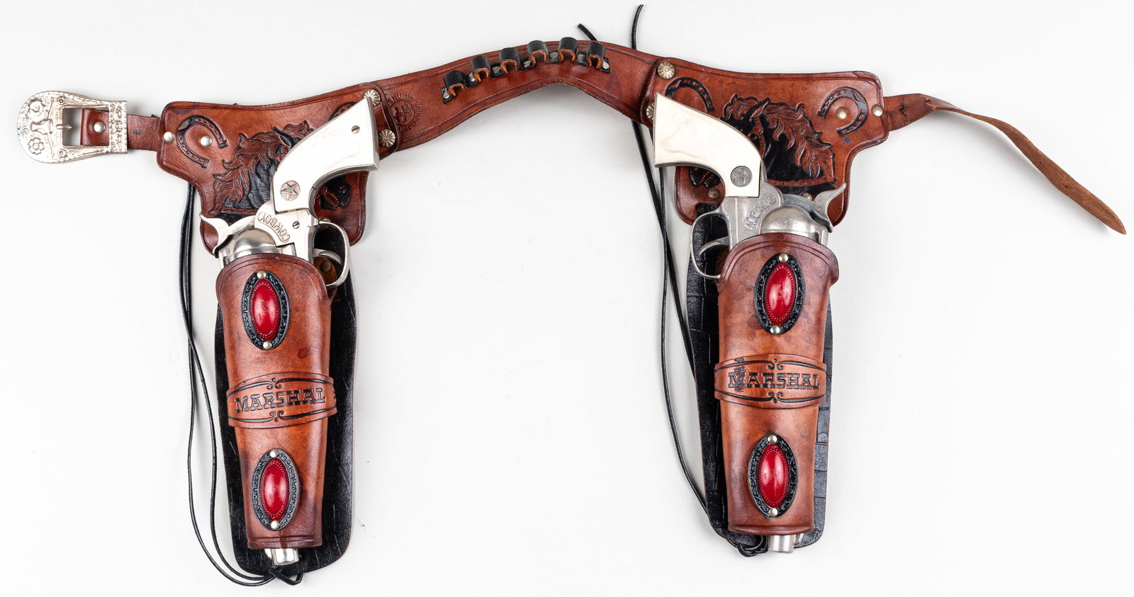 2 HUBLEY COWBOY REVOLVERS AND HOLSTER: Two Hubley die-cast 'Cowboy' revolver cap guns, 11.5 inches long, one revolver fully operational, one revolver not fully functional. With leather 'Marshal' holster belt, 32 inches long.