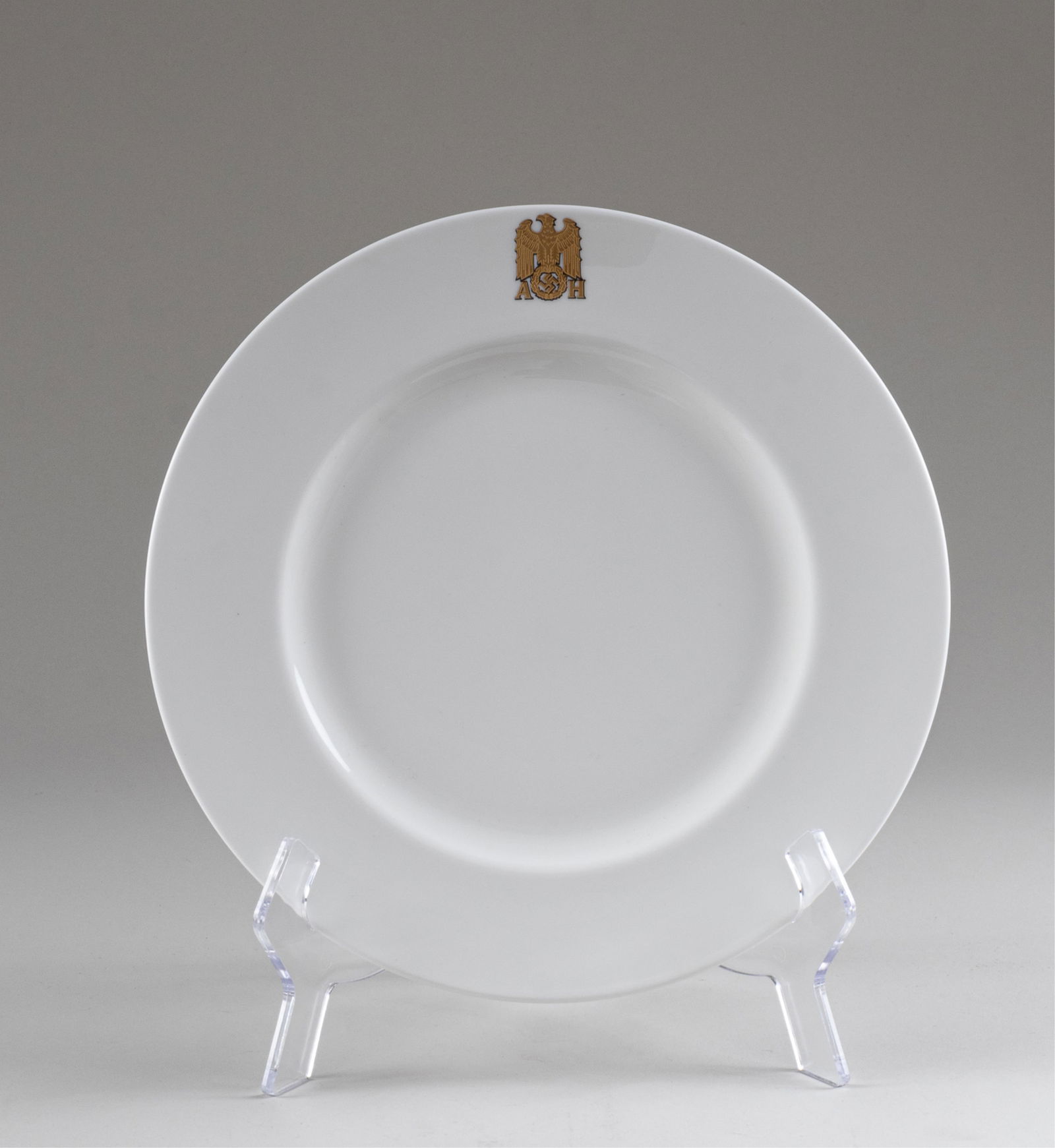 ADOLF HITLER ALLACH DINNER PLATE: WWII German Adolf Hitler dinner plate by Allach, white plate with gold colored WWII German eagle flanked by 'AH' at the top of the plate, on the bottom of the plate is stamped 'Allach.' 10.75 inches d