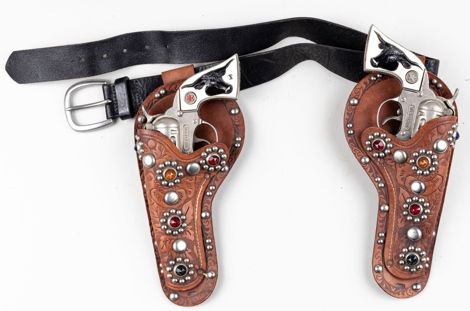 2 HUBLEY WESTERN CAP GUNS WITH HOLSTER: Two Hubley 'Western' revolver six-shooter cap guns. Die-cast metal cap gun. The toy guns show some signs of wear and scratches. The mechanisms are all in working order. Leather belt 38 inches long.