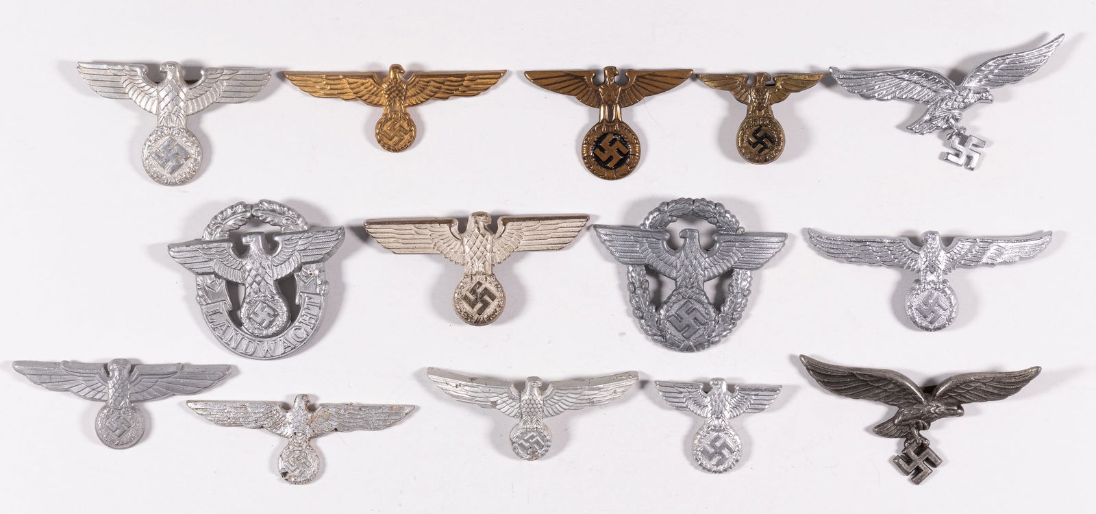 GERMAN EAGLE CAP BADGES (15): Lot of fifteen German eagle cap badges including badges for Wehrmact, Luftwaffe, Kriegsmarine, SA, SS, and Schutzpolizei. Also includes a breast eagle patch. Sold as is.