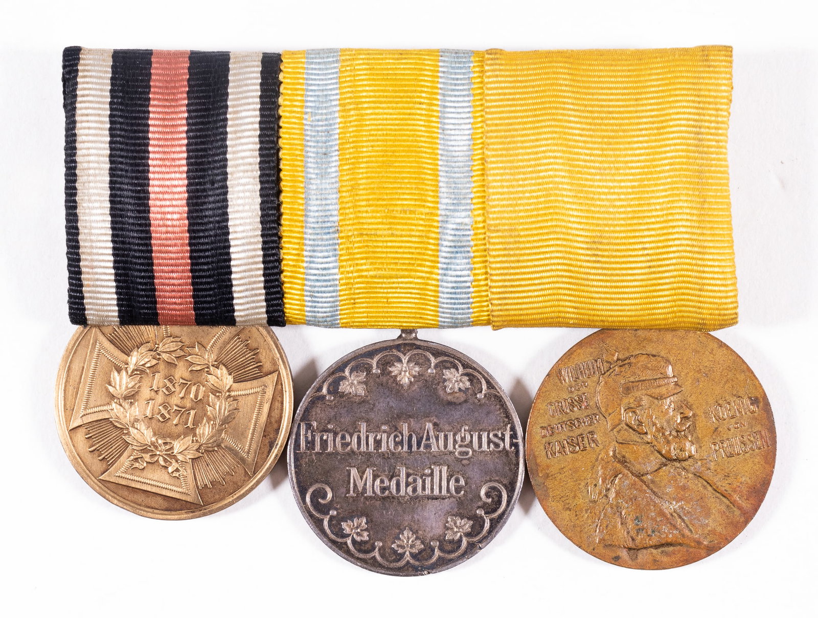 WWI IMPERIAL GERMAN MEDAL RIBBON BAR: WWI Imperial German medal ribbon bar with three medals attached including the Iron Cross second class, the Saxony Friedrich August medal in bronze, and the Kaiser Wilhelm I commemorative medal, ribbon