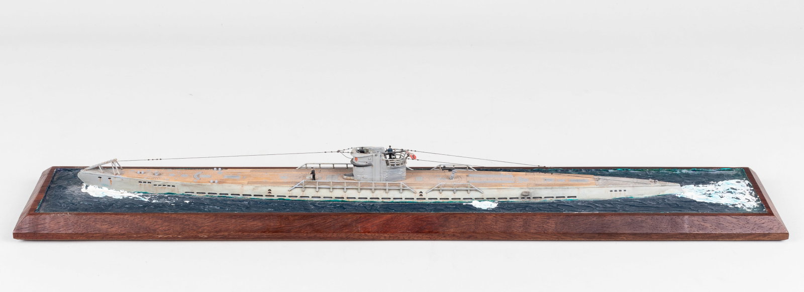 WWII GERMAN U-BOAT MODEL: A painted model based on a WWII German type-VIIC U-boat submarine displays the submarine floating above the water with little seamen on deck. 25.5 x 4.5 x 2.5 inches. Some parts missing from the model