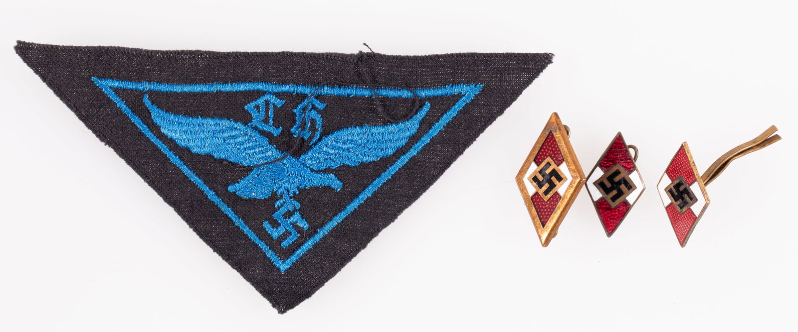 HITLER YOUTH BADGES AND INSIGNIA (4): Lot of four Hitler Youth badges and insignia including an insignia cap badge, two insignia pins, and one Flak Helpers patch. Each badge and pin marked on the reverse, one reads 'Ges. Gesch M1/70 8882,