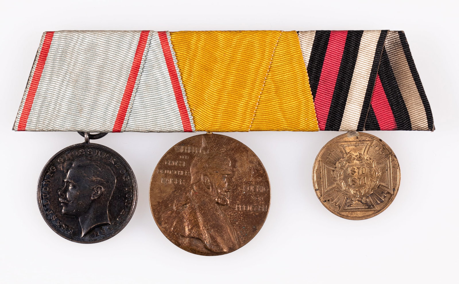 IMPERIAL GERMAN MEDAL BAR W/ 3 MEDALS: WWI Imperial German medal bar with three medals attached including the Hessen Bravery Medal, the Kaiser Wilhelm I Memorial medal, and the War Commemorative 1870-1871 medal.