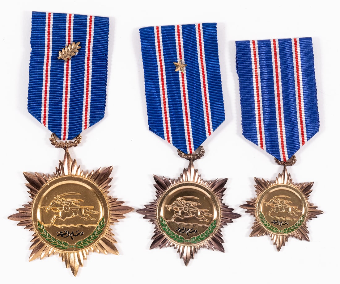 SYRIAN ORDER OF BRAVERY MEDALS ALL CLASSES: Lot of three Syrian Order of Bravery medals, one for each class, each a bronze gilt star with green and black enamel, 1st class with bronze palm on the ribbon, and 2nd class with bronze star on the ri