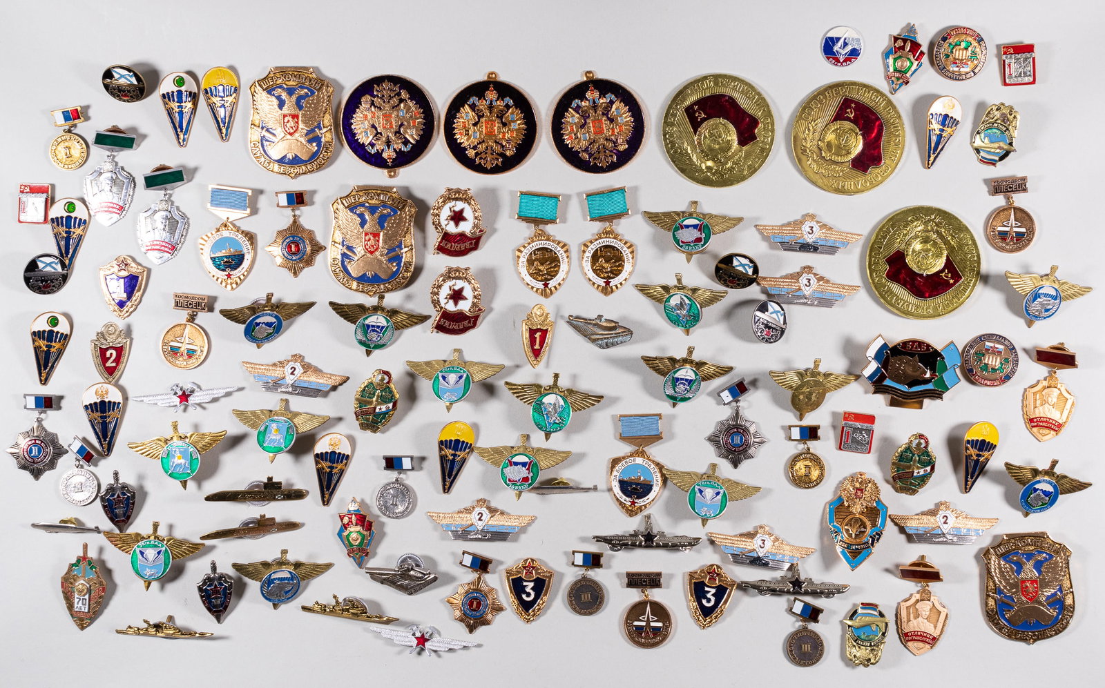 100 SOVIET PINS AND BADGES: Lot of 100 Soviet and Russian badges, including paratrooper badges, submariner badges, and others. Most are screw-back badge designs.