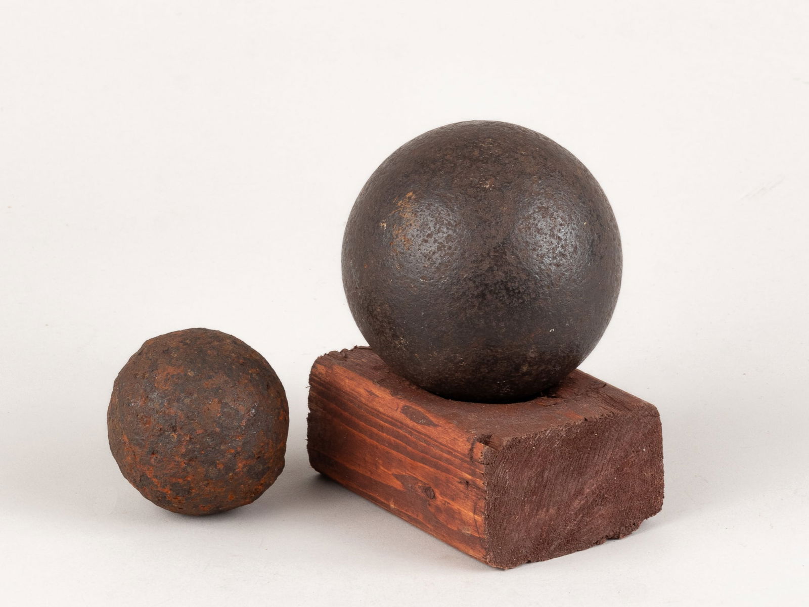2 CIVIL WAR CANNONBALLS: Lot of two Civil War cannonballs including one 3-inch diameter, 4 lbs ball, with wooden display stand, 3.5 x 2.5 x 1.25 inches, and one mini cannon shot ball 2.25 inches diameter, 1 lbs 3 oz.