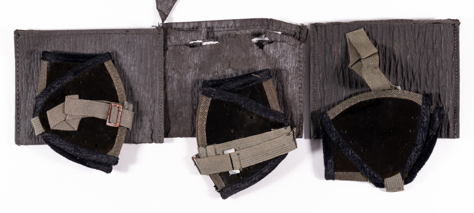 GERMAN AFRIKA KORPS SAND GOGGLES 3 PAIRS: Three pairs of German Afrika Korps sand goggles, used by German soldiers to help keep sand out of their eyes. All pairs are made of clear foldable lenses, with grey straps holding them together, and b
