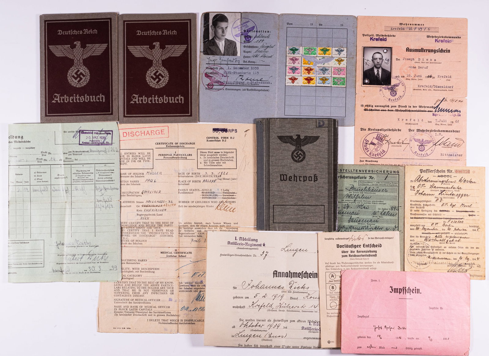 12 WWII WEHRPASS / WORK BOOKS / ID'S: Lot of twelve Third Reich ephemera pieces, including grouping from Johannes Dicks, with his Wehrpass, issued in Krefeld, July 1st, 1938, volunteer of the 1st Artillery 6th Regiment, his discharge pape