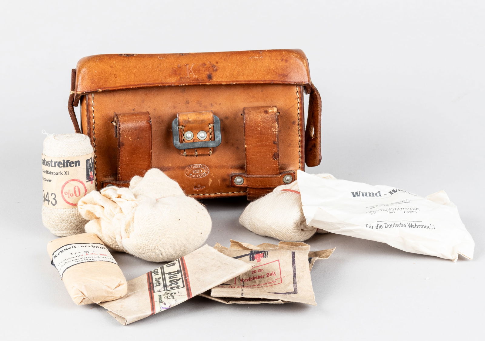 WWII GERMAN FIELD FIRST AID KIT 1939: WWII German field first aid kit, stamped on the front 'B.G.Leuner G.m.b.h. 1939 Bautzen,' with a Waffenamt stamp 'WaA169' at the bottom, and a contents list affixed on the inside of the lid. Tan leath