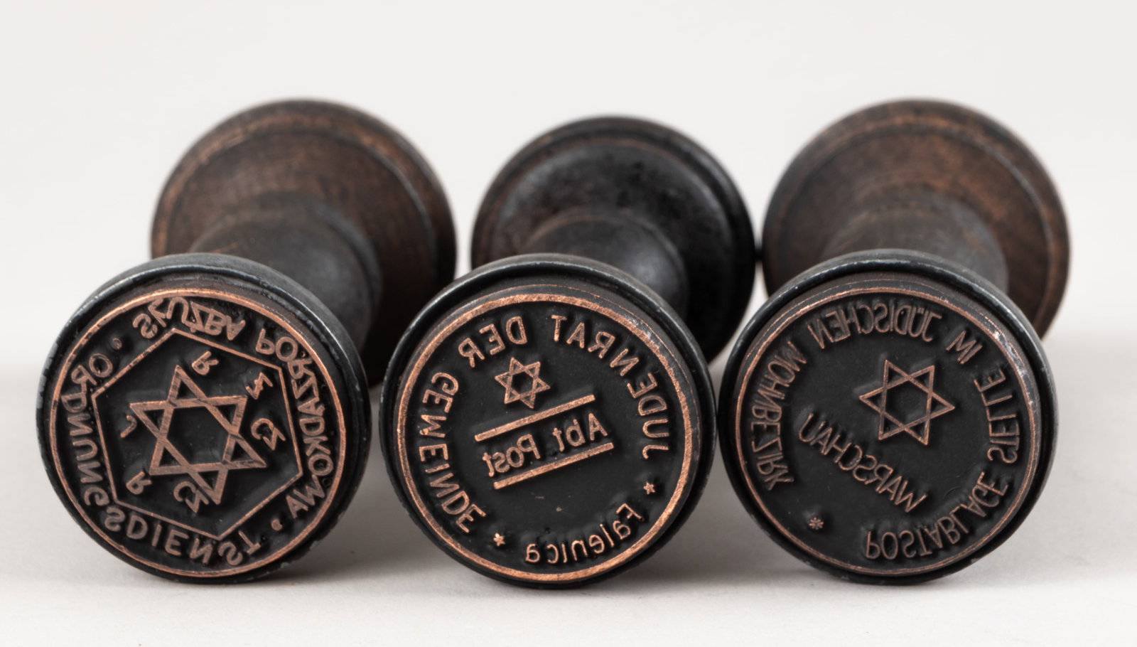 WWII WARSAW GHETTO HANDSTAMPS (3): Lot of three WWII Warsaw Ghetto handstamps with a wooden handle. The first stamp reads 'Ordnungsddienst STUZBA PORZADKOWA J R Cz R Z Cz' Jewish Ghetto Police, around a Star of David, one reads 'POSTAB