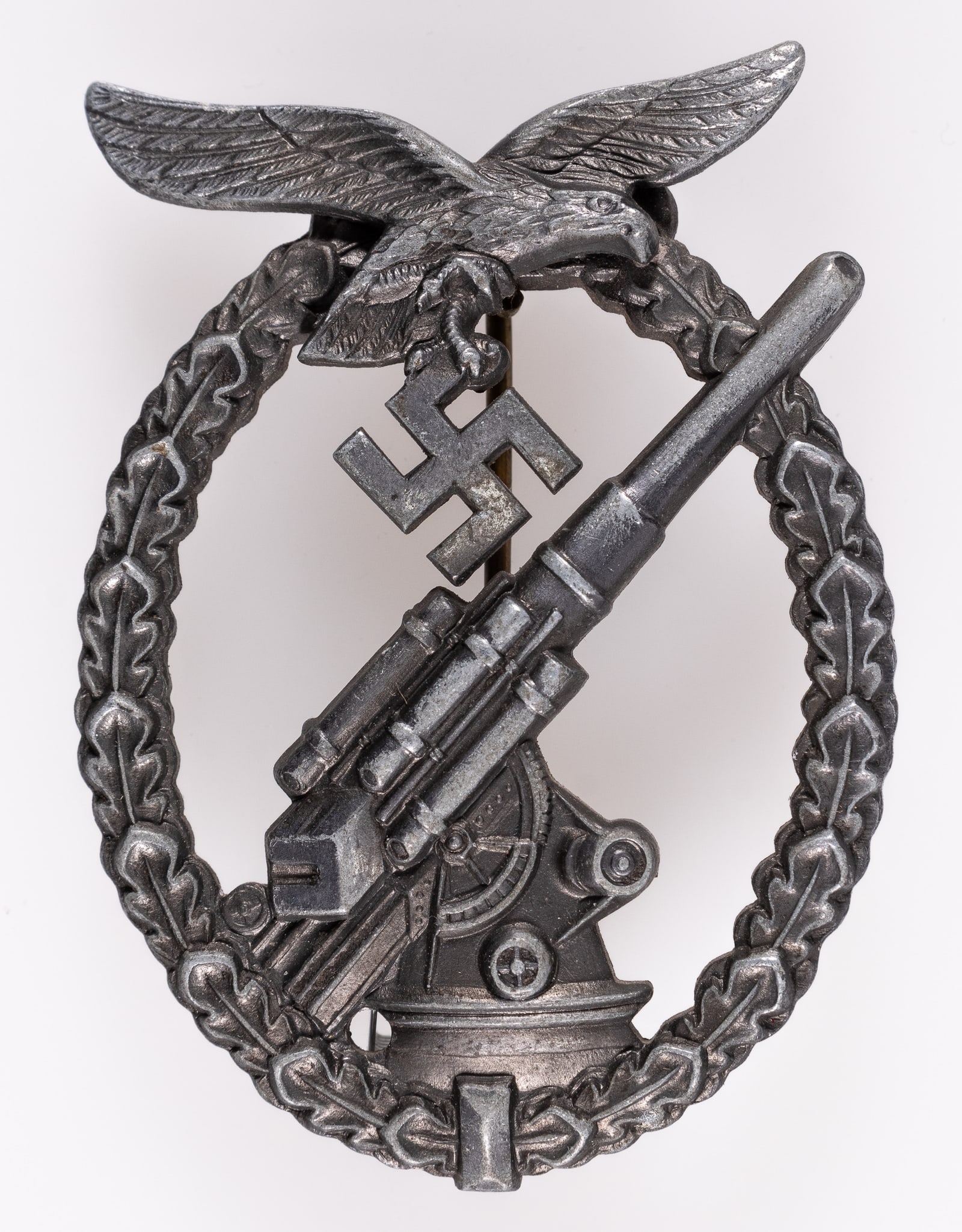 CASED LUFTWAFFE FLAK BADGE BERG & NOLTE: Cased Luftwaffe Flak Badge, by Berg & Nolte, Ludenscheid, with a blue case. Zinc badge with a Luftwaffe eagle clutching a swastika over a flak artillery cannon surrounded by a wreath of oak leaves, ap