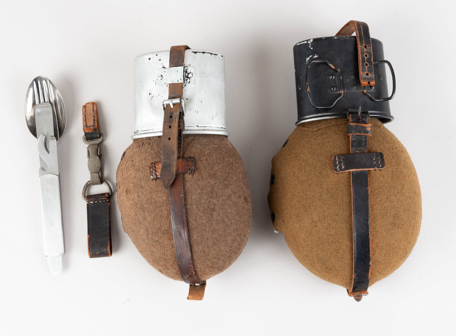 2 WWII GERMAN MEDIC FIELD WATER CANTEEN W/ UTENSILS: Lot of two WWII German Wehrmacht Medic's 1L field water canteen with felt wrap, leather strapping, an aluminum drinking cup, and a bakelite screw top. On the neck of one of the water bottle and the al