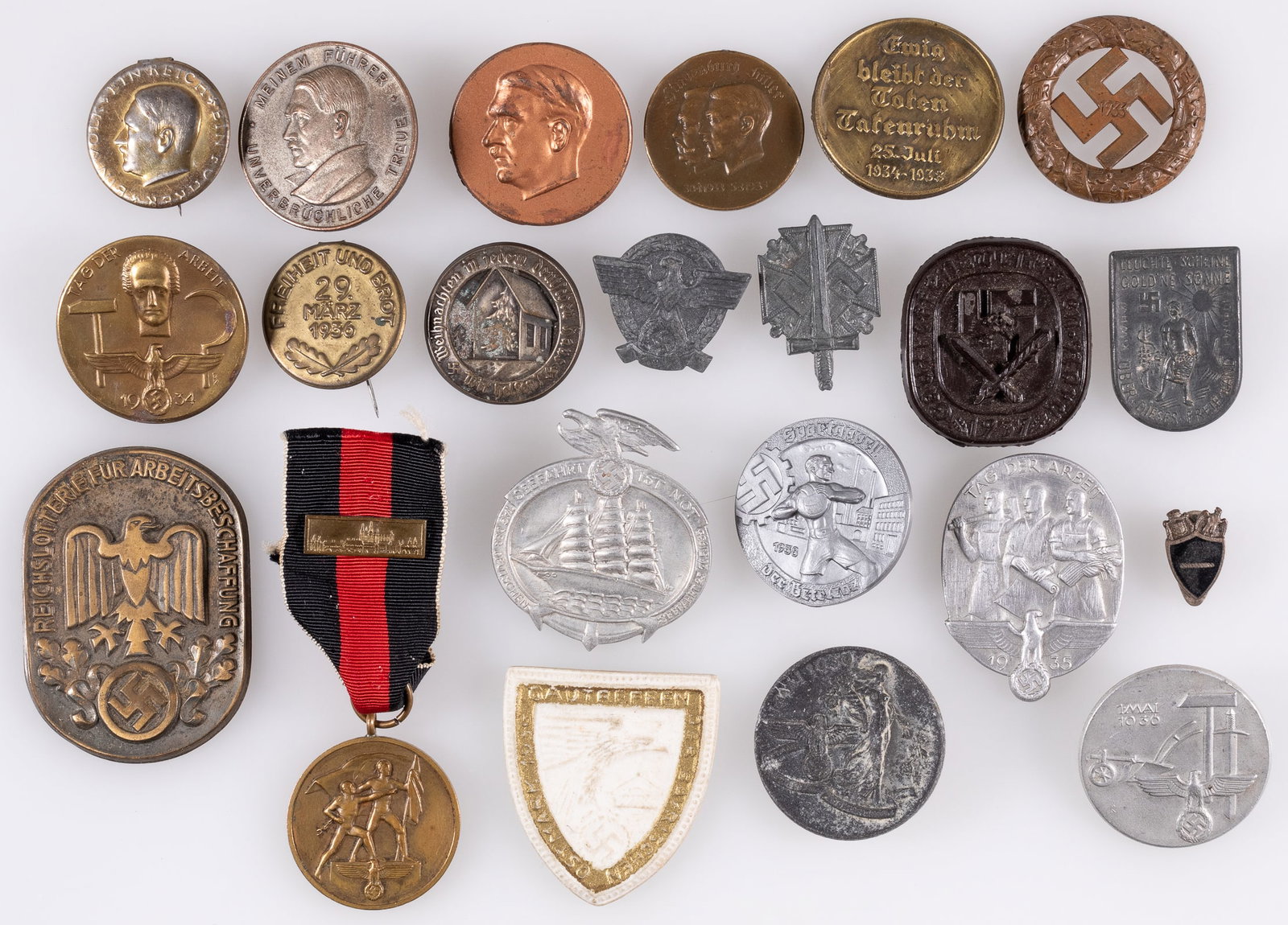22 GERMAN THIRD REICH TINNIES AND BADGES: Lot of twenty-two German Third Reich tinnies and badges, including Adolf Hitler pinbacks, large Reich lottery tinnie, no pin, Sudetenland medal with ribbon and clasp, along with other tinnies. Sold as