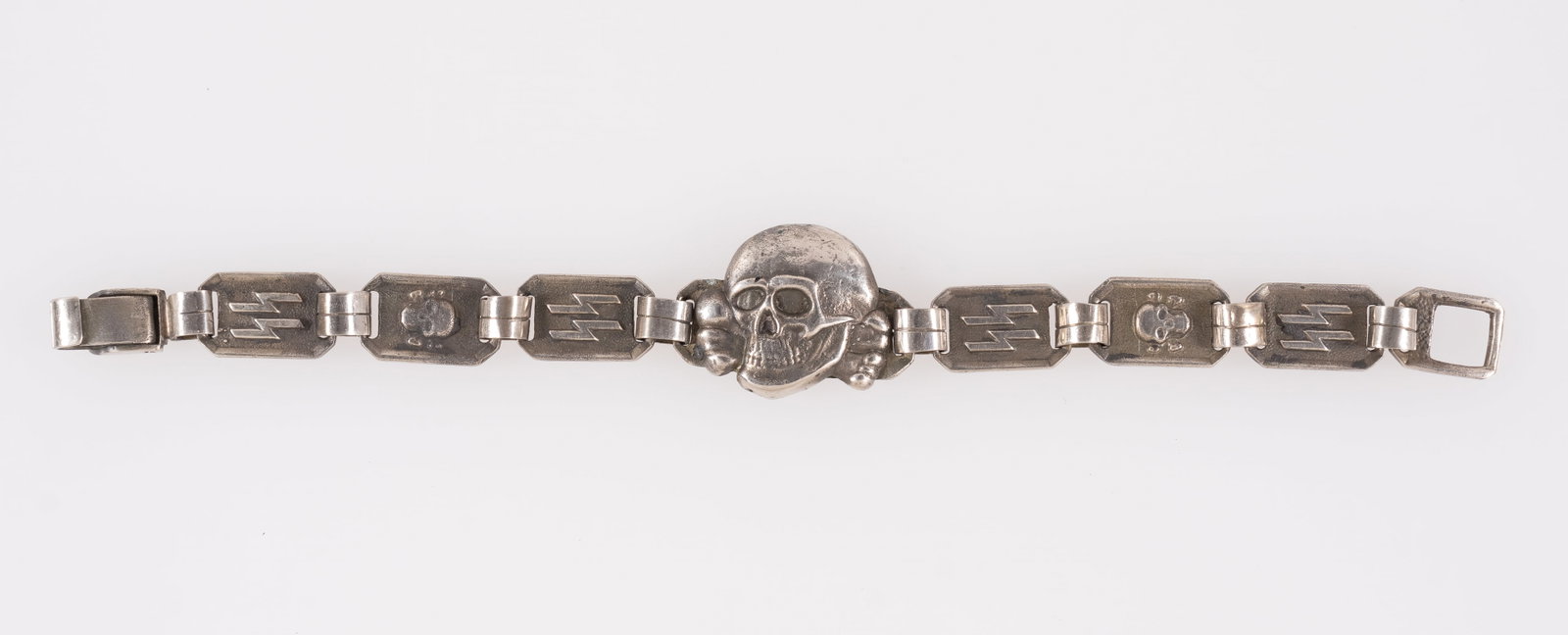 WAFFEN-SS TOTENKOPF BRACELET: Waffen-SS Totenkopf insignia bracelet, with a large Totenkopf skull in the center, and SS runes and a smaller Totenkopf on the bracelet band. On the reverse is stamped 'KH,' with maker marks above. 8.