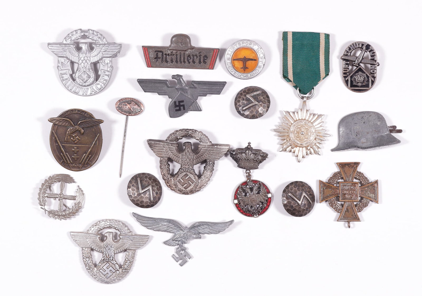 18 WWII GERMAN MEDALS, INSIGNIA, AND PINS: Eighteen WWII German medals, insignias, and pins, some include the Schutzpolizei cap badge marked 'A' for Assmann on the reverse, an Ostvolk medal, a Long Service medal in bronze, a Werkschutz visor c