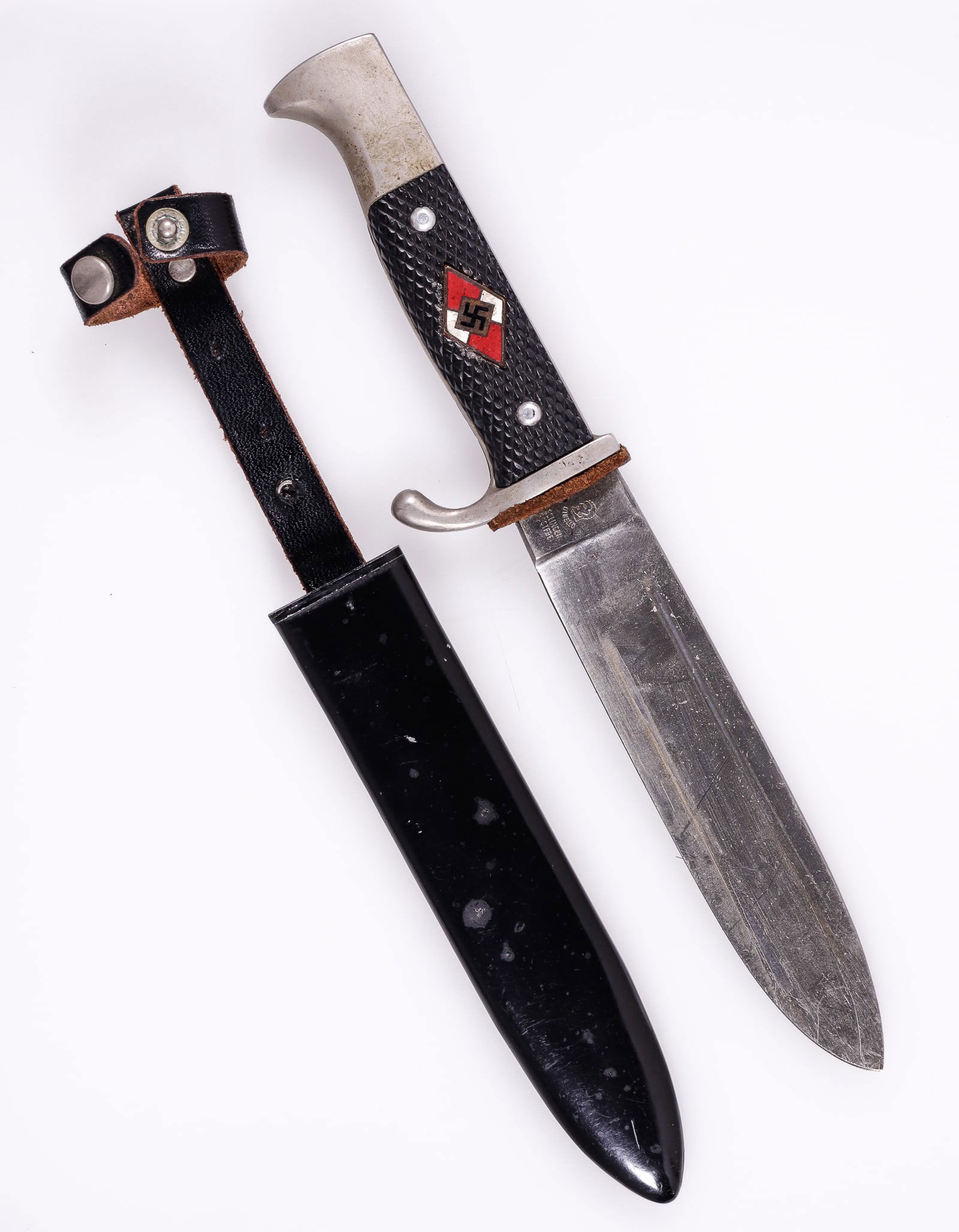 HITLER YOUTH POST-WAR KNIFE: Hitler Youth Knife, made post-war and marked on the ricasso 'Othello, Solingen, Rostfrei,' marked on the reverse 'Anton Wingen Jr., Solingen Germany.' With a metal scabbard and leather hanger, the lea