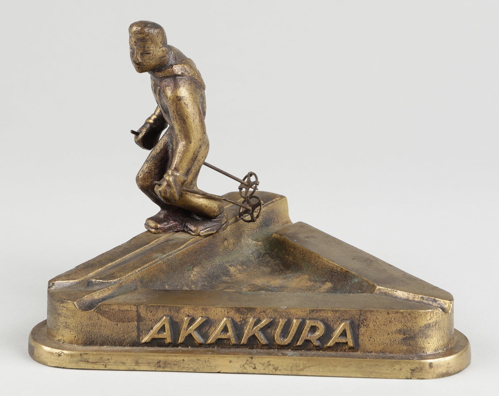 JAPANESE SKI RESORT SOUVENIR ASHTRAY: Japanese Ski Resort souvenir ashtray, triangular bronze ashtray with a figure of a skier, around the base reads 'Akakura, Myoko Plateau, Niigata, Japan.' 7.25 x 6.5 x 5.25 inches.
