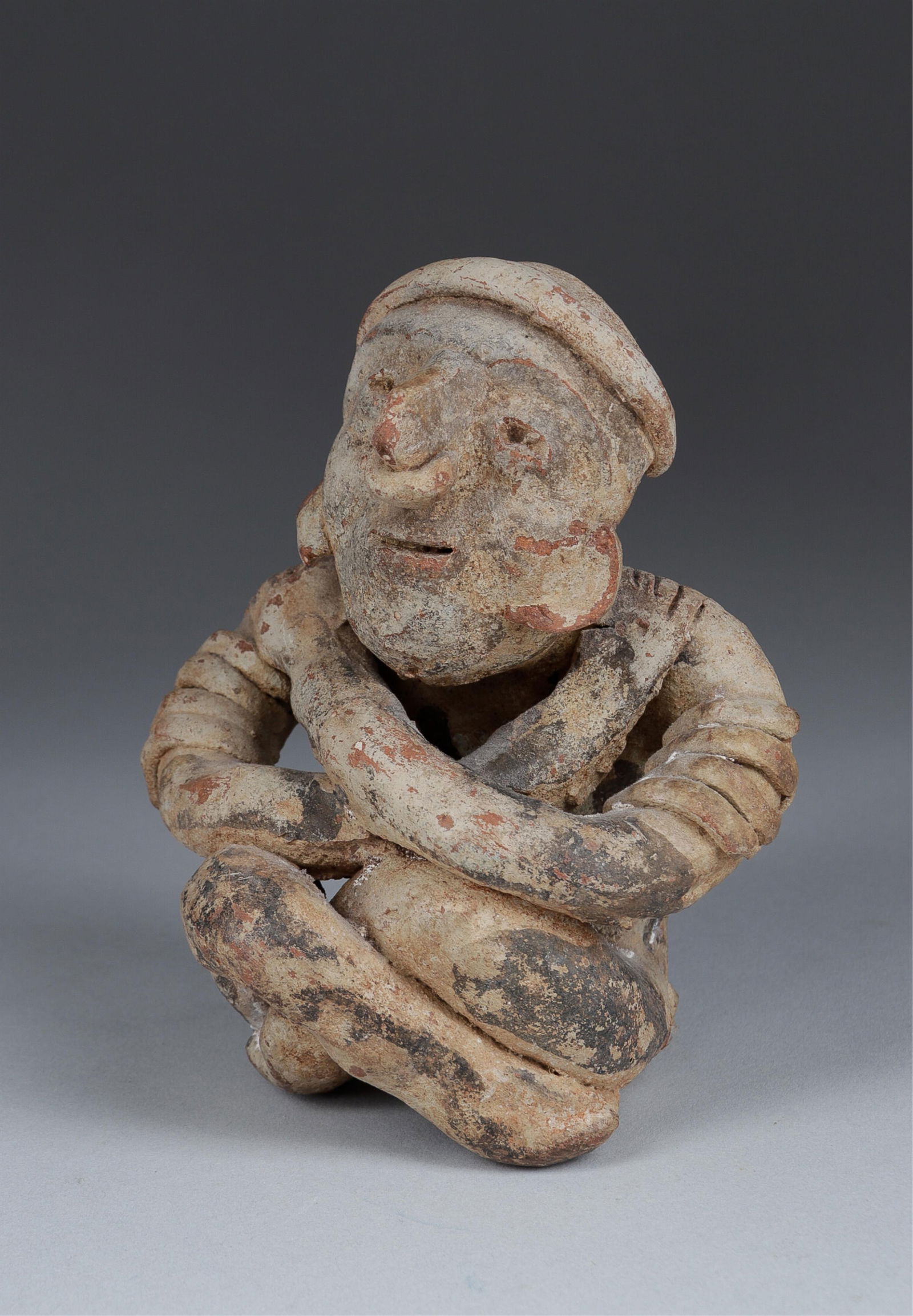 PRE-COLUMBIAN NAYARIT POTTERY SITTING FIGURE: Pre-Columbian Nayarit pottery of a sitting figure. 8 x 5.5 x 2.75 inches. From the collection of G. Theofiles.