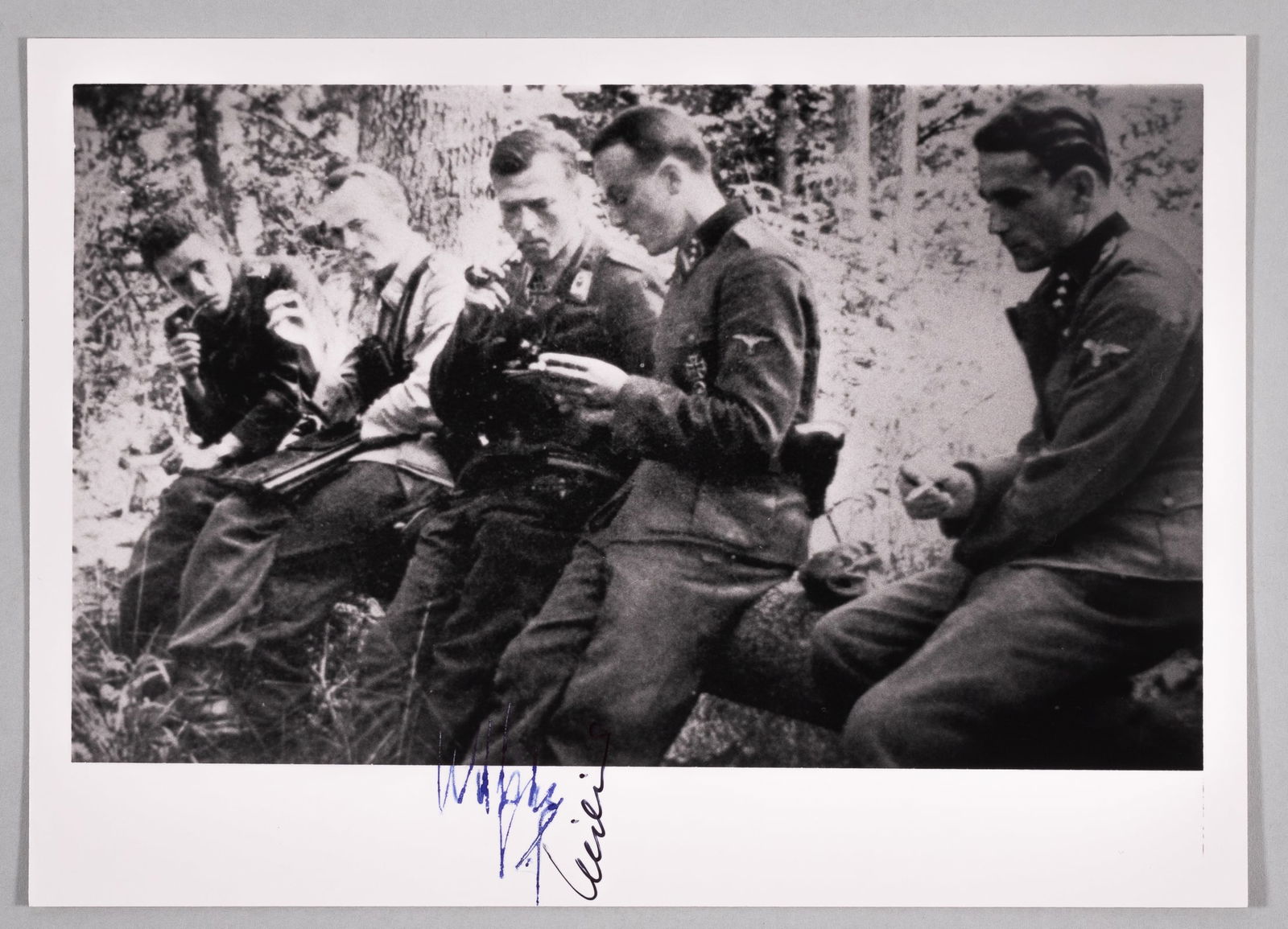 SIEGFRIED MILIUS - RUDOLF WITZIG: Black and white photograph of German officers sitting on a felled tree smoking their pipes, two included in the photo also autographed on the bottom margin underneath themselves in the photo. 5 x 7