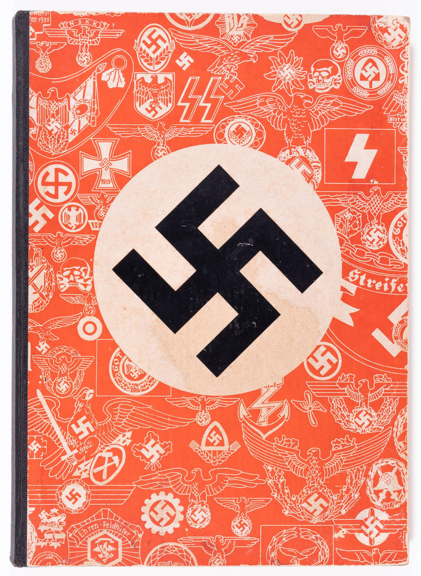 F. W. ASSMANN & SOHNE BADGE CATALOG: WWII hardbound F.W. Assmann & Sohne catalog. The company was known for making insignia and uniform metal accessories. Cover bears a large swastika surrounded by images of various company-made items. H