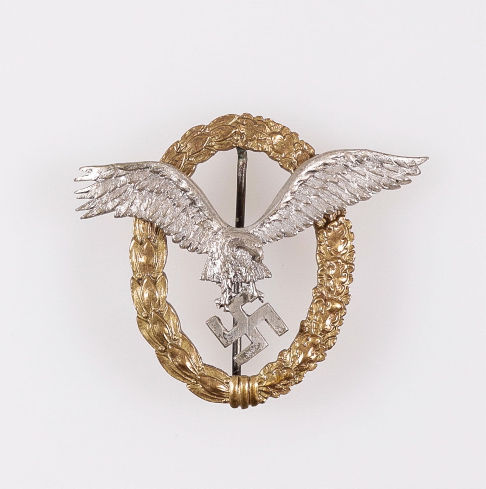WWII GERMAN LUFTWAFFE PILOT BADGE ASSMANN: WWII German Luftwaffe pilot's badge, on the reverse marked 'A' for maker Assmann. Luftwaffe insignia eagle clutching a swastika over a wreath of oak and laurel leaves. 52 mm tall, 64 mm wing span.