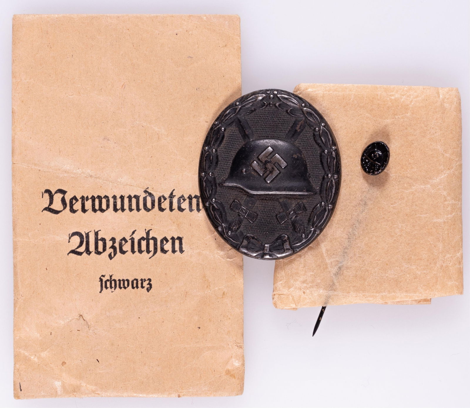 WWII GERMAN BLACK WOUND BADGE IN BLACK AND STICKPIN: WWII German black wound badge, marked on the reverse '65' for maker Klein & Quenzer, Idar-Oberstein. Hollow back, c-clasp vertical pin, with a paper envelope stamped Fritz Kohm, Pforzheim. With an unm