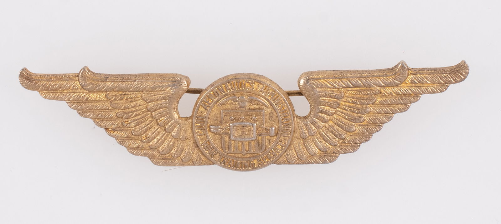WWII CAA WAR TRAINING STERLING WINGS IN GOLD: WWII-era US Civil Aeronautics Administration War Training Service sterling pilot wings badge in gold, c-clasp pinback, marked 'PAT. PEND. STERLING' on the reverse, faded gold wash, 3 inches long.