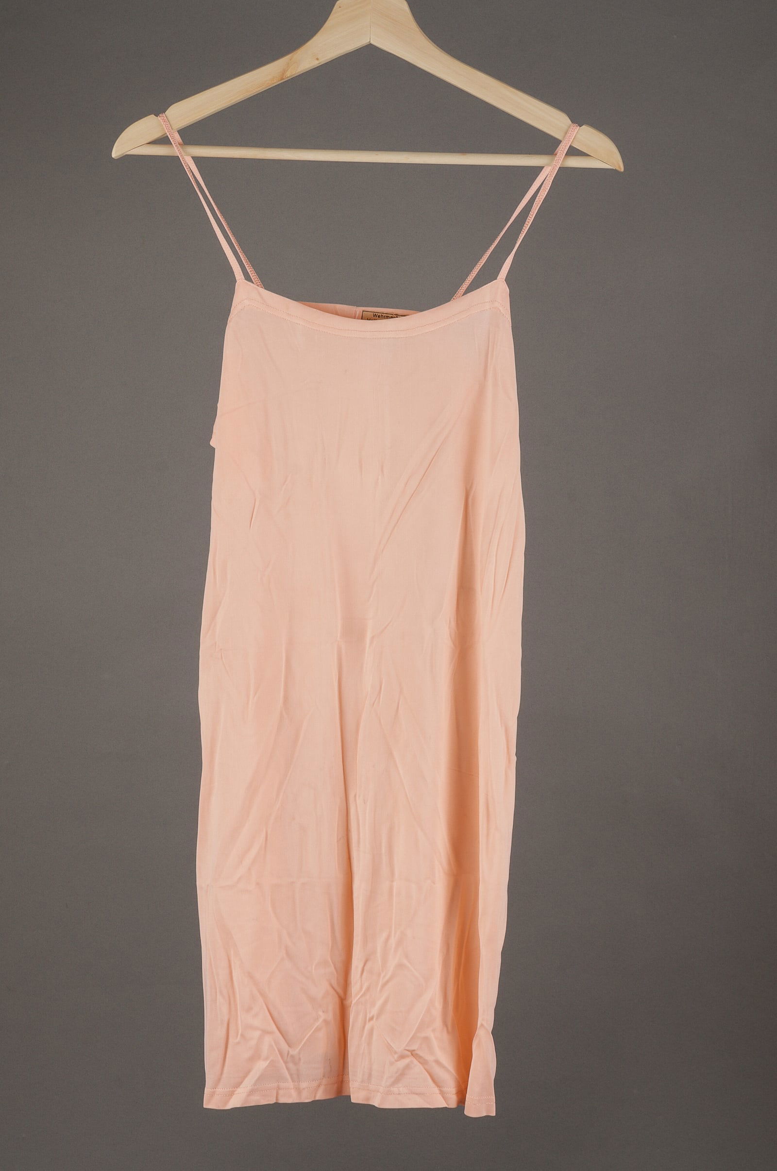 WEHRMACHT HELFERINNEN SLIP UNDERSHIRT: Undershirt slip from Helferinnen Korps (Women's Helper Corps) from 1945, salmon color shirt with original Wehrmacht tag still attached. Reads 'Wehrmacht-Helferinnenkorps Liefenrant: Artikel: