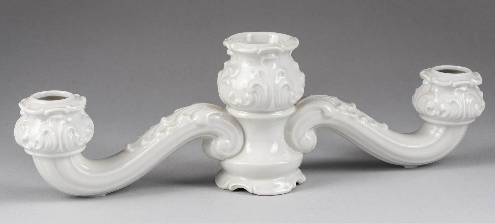 ALLACH CANDLE HOLDER MODEL 23 FRANZ NAGY: Allach porcelain three candle holder, model #23, designed by Franz Nagy, features a center candle holder with two scrolled arms decorated with floral motifs. Fine white glazed porcelain. Allach mark a