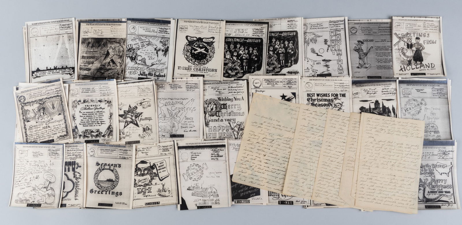 70 WWII V-MAIL SEASONS GREETINGS CARDS: Seventy WWII V-Mail Seasons Greetings cards, transmittal copies sent to families from soldiers, most cards featuring art illustrated by members of the soldiers' unit, graphic designs, and poems.