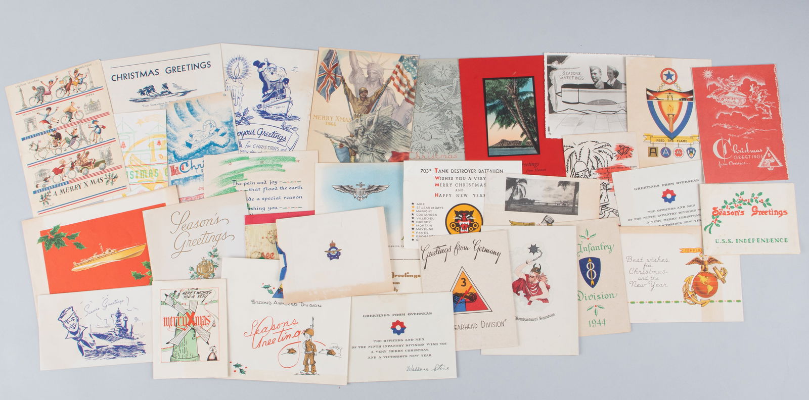 31 WWII AMERICAN CHRISTMAS CARDS: Thirty-one WWII American Christmas cards, most featuring unit insignia or other military imagery, some with messages written on them, and with their original transmission envelope.