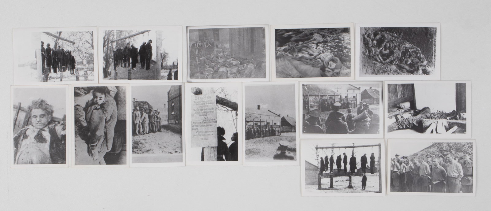14 PHOTOGRAPHS OF HOLOCAUST NAZI ATROCITIES: Fourteen black and white photographs of Nazi atrocities. Photos feature many dead victims of the Holocaust, with some close-up shots of dead bodies, firing squad lines, and an emaciated child. Photogr