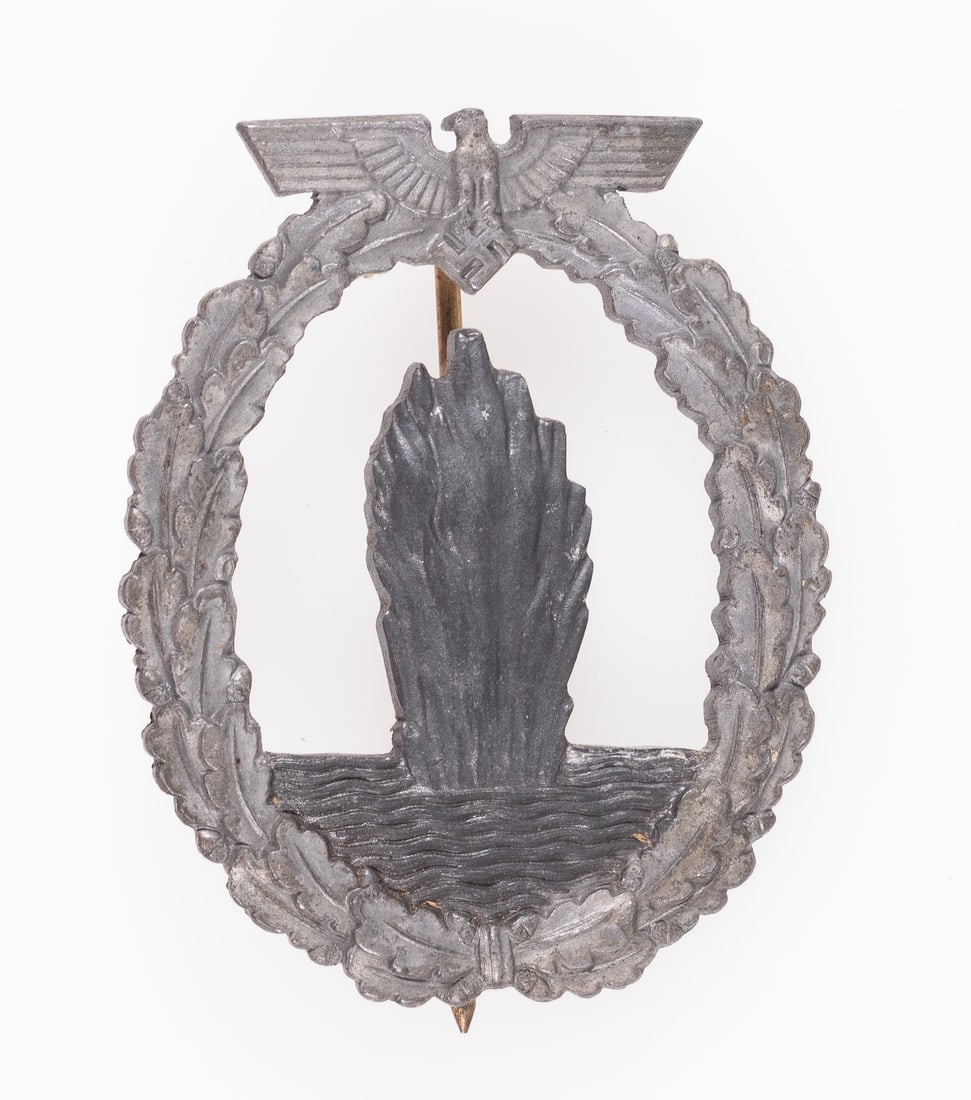 WWII GERMAN MINESWEEPER BADGE ALOIS RETTENMAIER: WWII German Minesweeper badge, unmarked but with features attributing the badge to Alois Rettenmaier, Schwabisch-Gmund; zinc construction with most of the gold wash missing. A C-clasp pinback that has