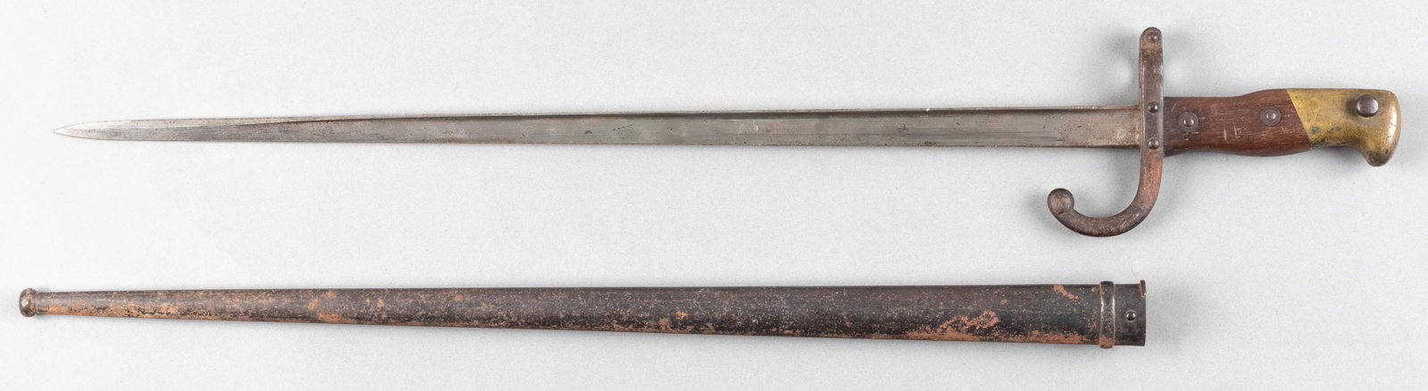 FRENCH M1874 GRAS RIFLE BAYONET: French M1874 Gras Rifle bayonet, with a brass pommel, wooden grips, metal cross guard, and steel blade. Engraved on the spine of the blade, 'Mre d'Armes de St.-Étienne Janvier 1879' for the manuf