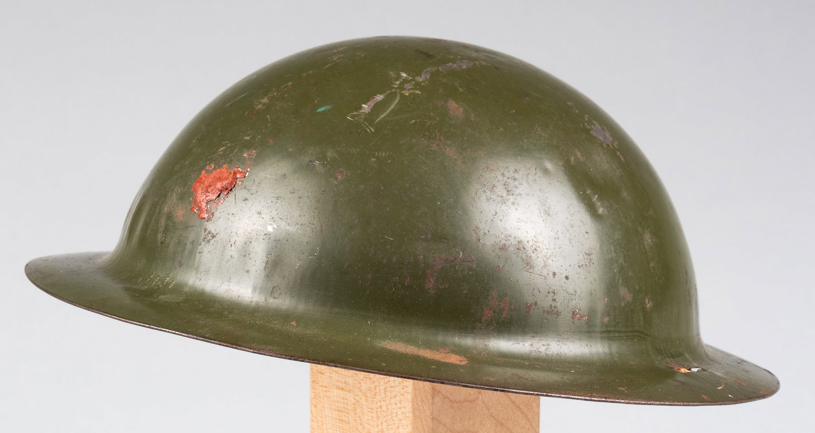 WWII U.S. CHILD HELMET: WWII U.S. child helmet, no markings, fabric chinstrap, and leather pad in the crown. Many dents throughout the top of the helmet.