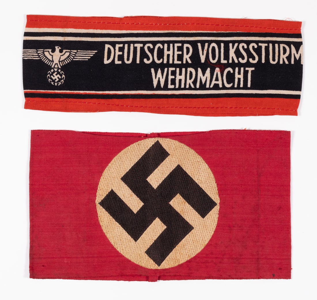 2 WWII NSDAP PARTY ARMBAND AND VOLKSSTURM ARMBAND: Two WWII Nazi armbands, including a simple 3-piece NSDAP party armband, red cloth with a white disk and black swastika sewn to it, stitched at one end to form an armband. Toning throughout. 4 x 7