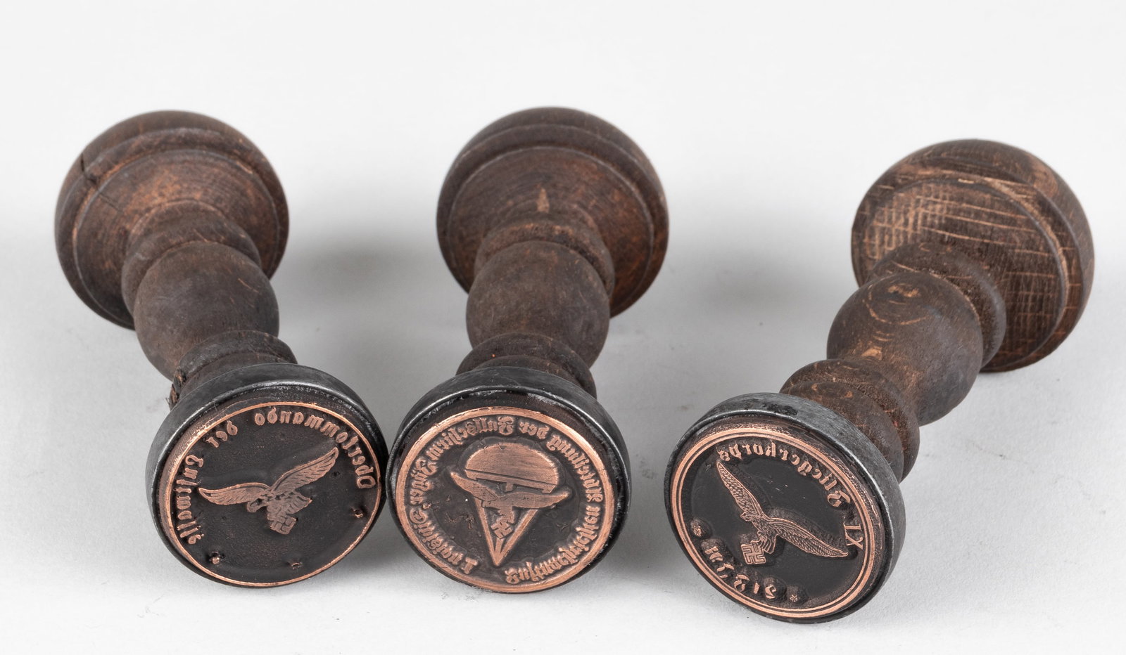 WWII GERMAN LUFTWAFFE HANDSTAMPS: Three wooden handstamps. The first stamp reads 'Oberkommando der Luftwaffe,' ‘Luftnachrichtenabteilung der Fallschirmjagerdivision 1,’ and ‘XI Fliegerkorps,’ with the German Lu