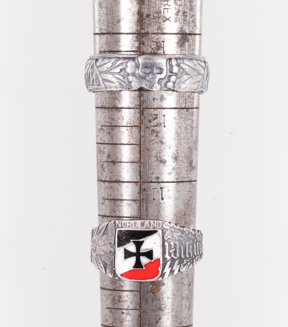 GERMAN WEHRMACHT SS RINGS (2): Pair of German military SS rings, a skull-and-crossbones 'Totenkopf' ring, silver, and one Viking ring with an Iron Cross on a German tricolor shield, approx. 22mm ring size.