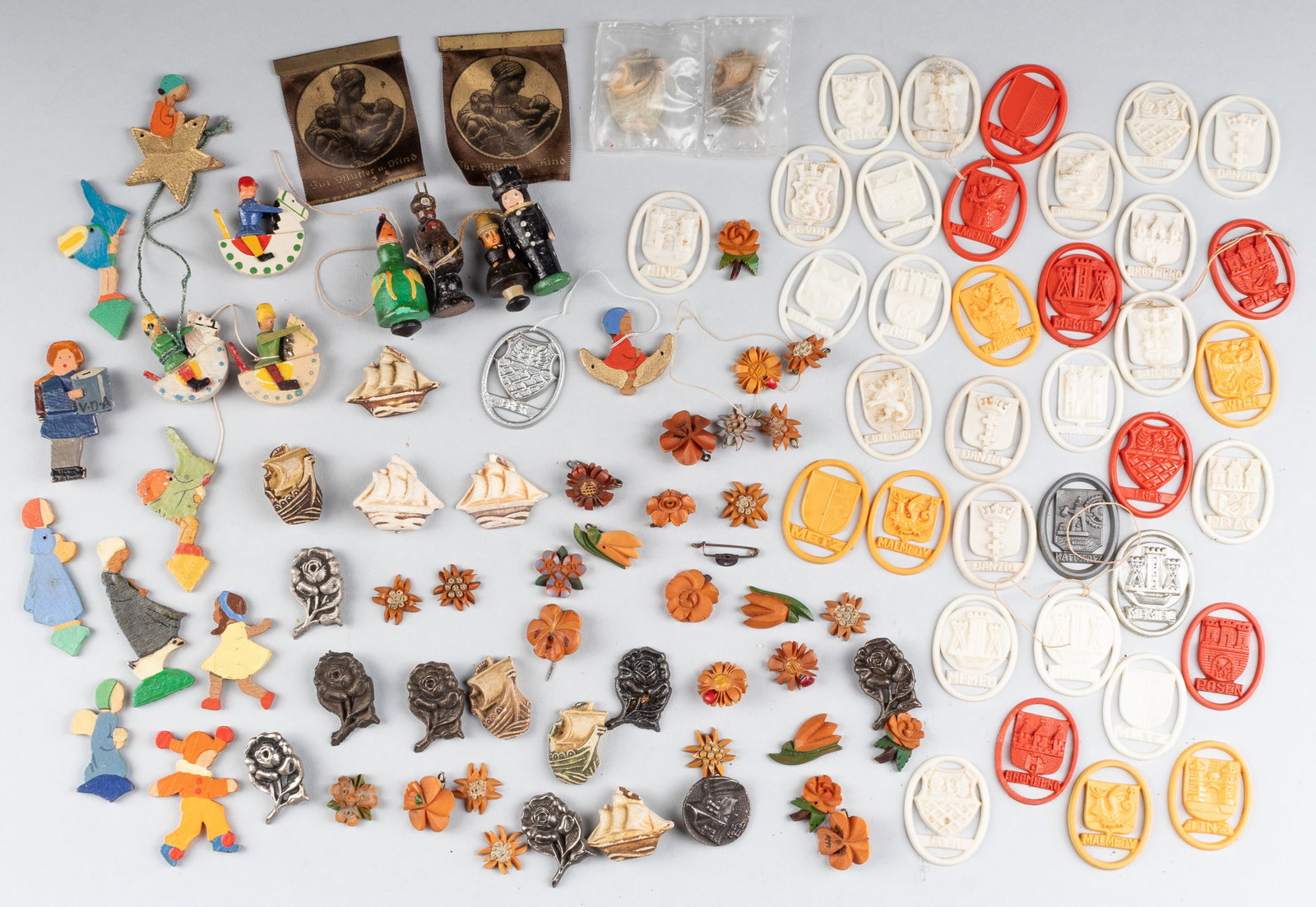 100 WHW WINTERHILFSWERK TOKENS: Approx. 100 WHW Winterhilfswerk donation tokens, handmade wood figurines, iron roses, clay sailing ships, flowers, colored plastic city and region tokens. Some are missing the pin. Some were issues wi