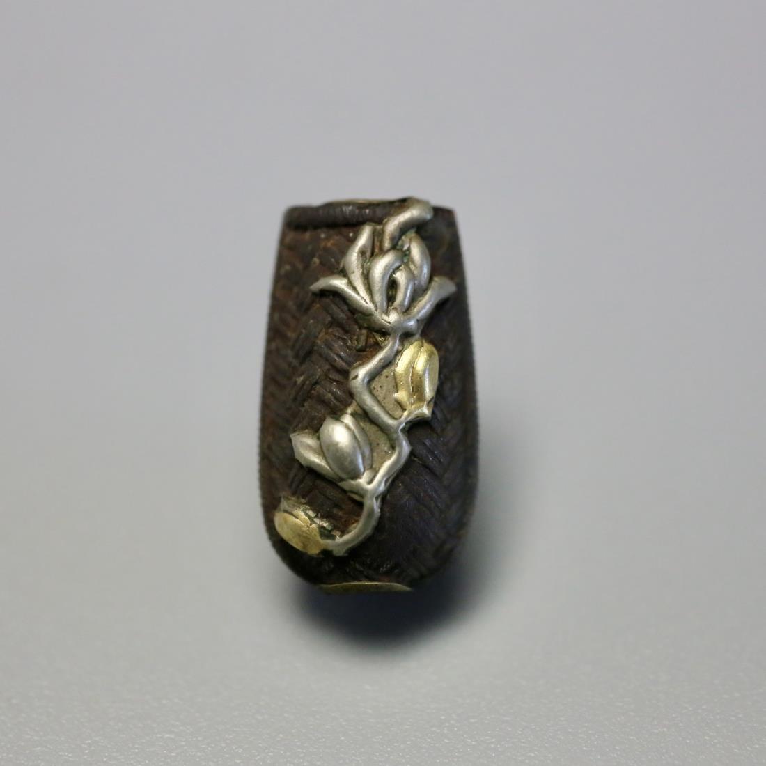 A SILVER INLAID 'FLOWER' COPPER OJIME BEAD: A silver inlaid 'flower' copper Ojime Bead, Japanese Meiji Era. Dimensions: H 1.9 cm, W 1 cm. Weight: 2.44 g. All measurements are approximate. Provenance: property from a private collector in Pittsbu