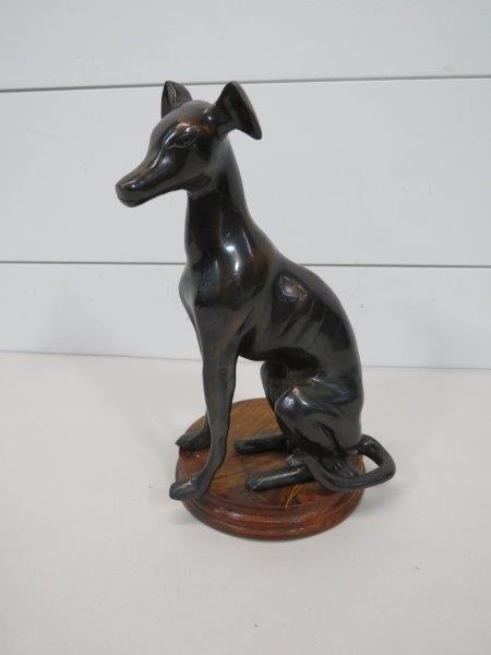 Maitland-Smith Style Seated Greyhound Whippet Figurine: Cast metal stylized seated male greyhound or whippet in the style of Maitland-Smith. Japaning finish over what is believed to be brass. On wooden circular base. Old felt to the underside. The base doe